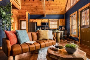 Ein gemütliches Cabin-Interieur mit Ledersofa, Holzschränken, einem Essbereich und einer Küche.