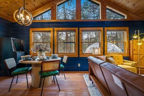 Ein gemütliches Blockhaus-Interieur mit Essbereich, einer Couch und großen Fenstern.