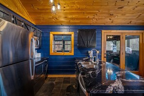 Eine moderne Küche mit Edelstahlgeräten, einer schwarzen Marmorarbeitsplatte und einer Holzbalkendecke.