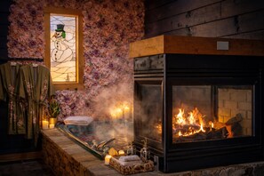 A cozy room with a fireplace, a bathtub, and a floral wall. - Gatlinburg Oasis|4Mi to Downtown|Hot Tub (Sevierville)