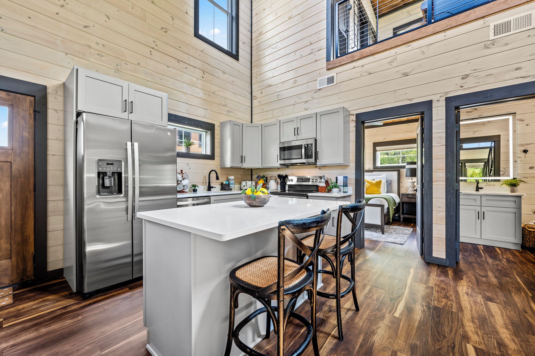 A modern kitchen with a central island, stainless steel appliances, and wooden flooring.