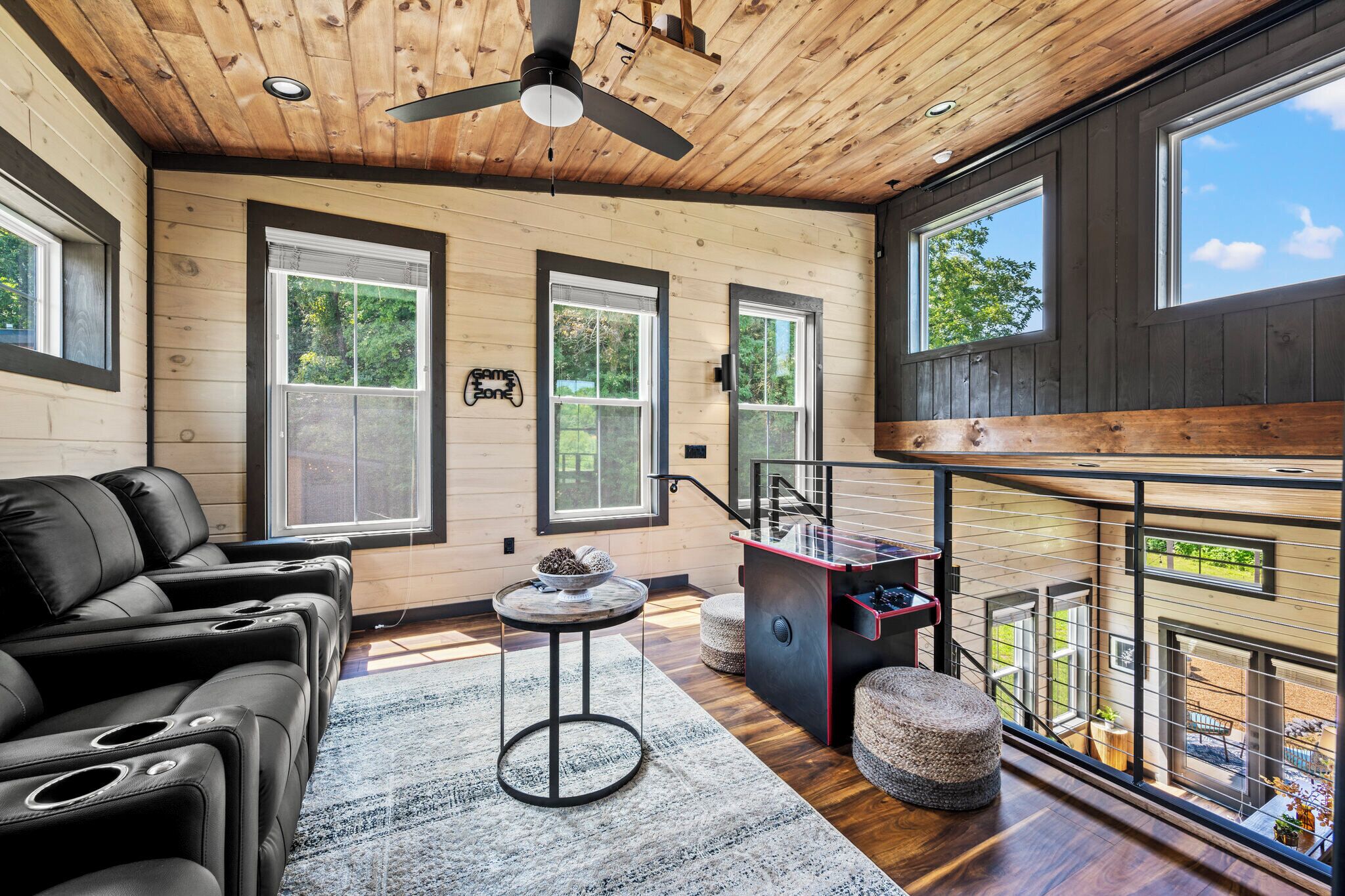 A modern interior with a wooden ceiling, large windows, a sofa, a small table, and a staircase.