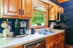 A kitchen with wooden cabinets, a coffee maker, a kettle, and a microwave. - Romantic Cabin w/ Hot Tub • 3mi to Pigeon Forge • King Bed • Fireplace (Pigeon For)