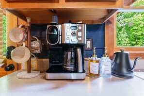 A compact kitchen with a coffee maker, two bottles of syrup, and a kettle. - Romantic Cabin w/ Hot Tub • 3mi to Pigeon Forge • King Bed • Fireplace (Pigeon For)