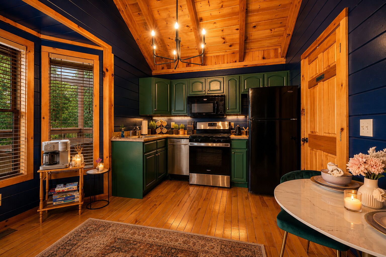 A modern kitchen with green cabinets, stainless steel appliances, and a wooden ceiling.