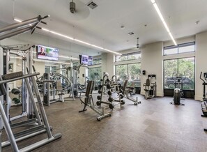 A gym with various exercise equipment, large windows, and a television screen. - 2-bedroom apartment in lovely La Cantera Area with Pool View (San Antonio)