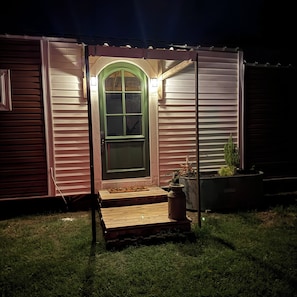 A house with a green door, a wooden porch, and a potted plant.