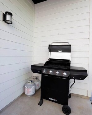 A black NexGrill barbecue grill with four burners, two propane tanks, and a side table. - Summer + Fall Rates - 4BR - Game Nights + Backyard Vibes - 5 Min Dtwn (Dallas)