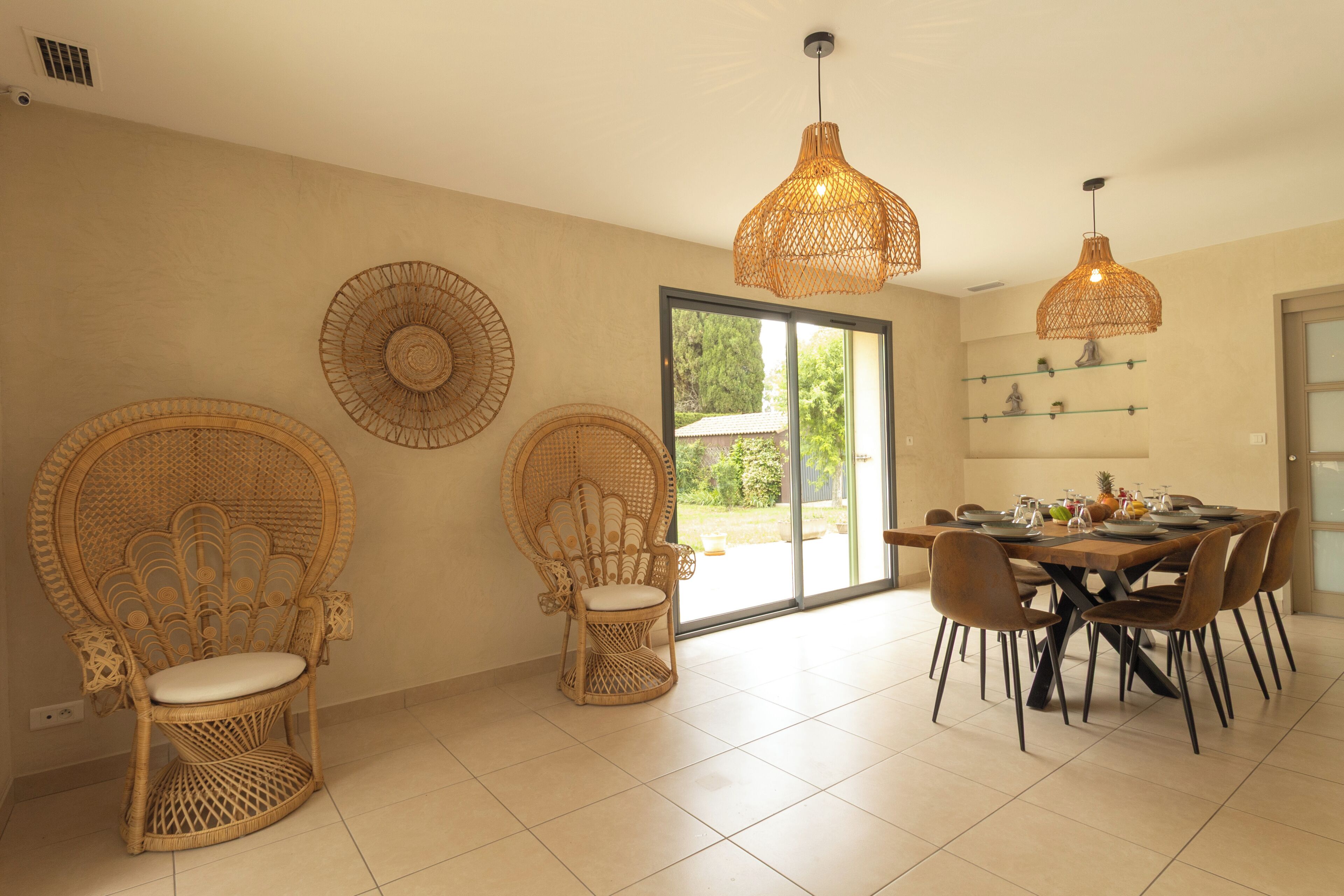 A dining area with wicker chairs, a round table, and pendant lights.