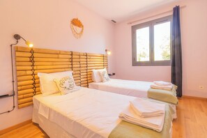 Een hotelkamer met twee bedden, een groot raam en een decoratief object aan de muur.