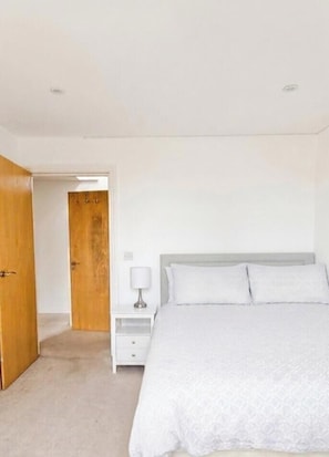 A bedroom with a bed, a nightstand, and a door. - Excellent 2 Bedroom Flat Next to Everything (Cambridge)