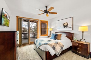 A bedroom with a bed, a nightstand, a lamp, a ceiling fan, and a door leading to a balcony. - Private Hot Tub, Pool, Ski Shuttle, Garage, Boot Warmer, Grill, Shuffle Board (Steamboat Springs)