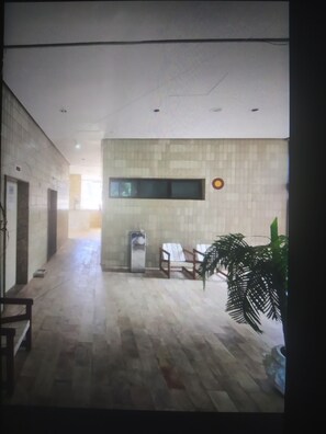 A hallway with a tiled floor, a water dispenser, a chair, and a potted plant. - LIBERDADE SQUARE/SAVASSI (Belo Horizonte)