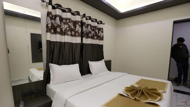 Une chambre d’hôtel avec un lit, un miroir, des rideaux et une porte.