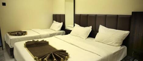 A hotel room with two beds, a large mirror, and a bedside telephone.