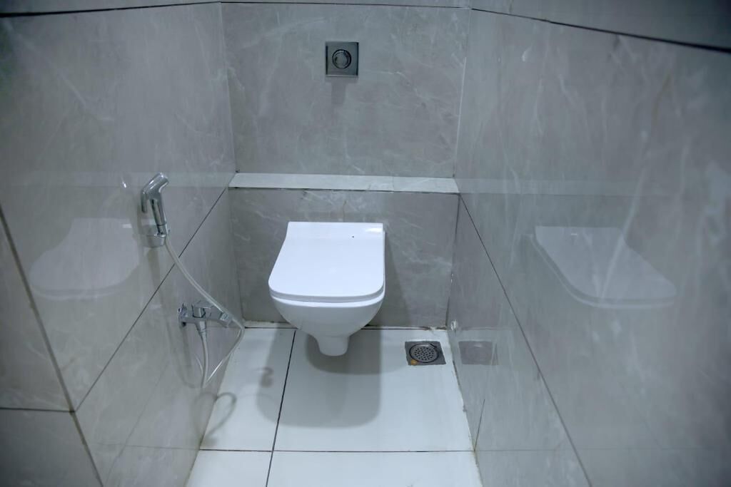 A small, enclosed bathroom with a toilet, a shower, and a sink.