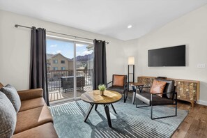 A modern living room with a sofa, armchairs, a coffee table, and a TV mounted on the wall. - 4-I White Rim Redcliff Condo (Top Floor) (Moab)