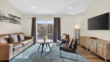 Un salon moderne avec un canapé en cuir, une table basse et un téléviseur fixé au mur.