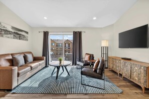 A modern living room with a leather sofa, a coffee table, and a TV mounted on the wall. - 4-I White Rim Redcliff Condo (Top Floor) (Moab)