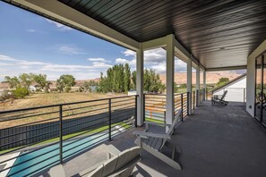 Un'area esterna coperta con piscina, posti a sedere e vista sul paesaggio circostante.