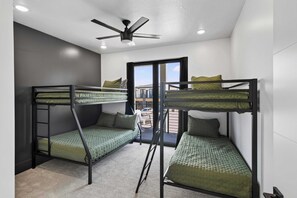 A room with bunk beds, a ceiling fan, and a view through a glass door. - Moab Desert Oasis Pool Spa Red Rock Views (Moab)