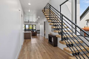 Ein modernes Interieur mit einer Holztreppe, einer Küche mit Holdelementen und einem Essbereich mit einer Couch.
