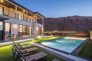 A modern two-story house with a swimming pool, outdoor seating, and a view of a mountain range. - Moab Desert Oasis Pool Spa Red Rock Views (Moab)
