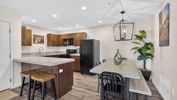 Eine Küche mit Holzausstattung, einer Granit Arbeitsplatte, einem schwarzen Kühlschrank und einem Essbereich mit Tisch und Stühlen.