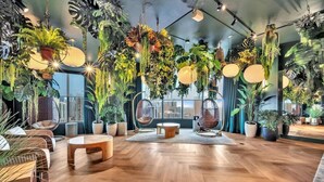 A modern interior with wooden flooring, hanging plants, and seating areas. - Urban Escape Suite | Ocean View | Downtown (Miami)