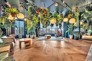 Ein modernes Interieur mit Holzböden, hängenden Pflanzen und Sitzbereichen.