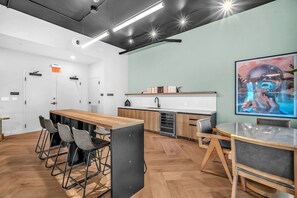 A modern kitchen with a wooden countertop, a sink, and a stove. There is a dining area with a long table and chairs. - Urban Escape Suite | Ocean View | Downtown (Miami)