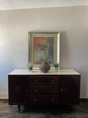 A dark wooden cabinet with three drawers, a decorative vase, and two potted plants on top. - Lovely 1-bedroom Rental Unit in Mazatlán Centro (Mazatlán)