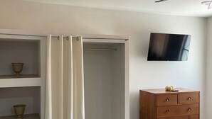 A room with a walk-in closet, a wooden dresser, and a flat-screen TV mounted on the wall. - Lovely 1-bedroom Rental Unit in Mazatlán Centro (Mazatlán)