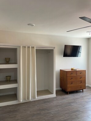 A room with a walk-in closet, a wooden dresser, and a flat-screen TV mounted on the wall. - Lovely 1-bedroom Rental Unit in Mazatlán Centro (Mazatlán)