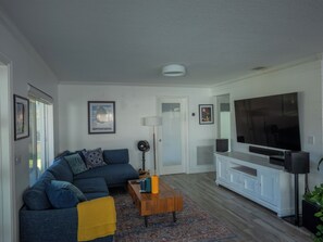 A modern living room with a sofa, a coffee table, a TV, and a large window. - 3BR 2BA house, Jacuzzi, Minutes to beach, in fabulous Fort Lauderdale with AC (Fort Lauderdale)