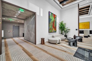 A modern lobby with a seating area, a large abstract painting, and a plant. - Brand New Building & Amazing Amenities (Miami)