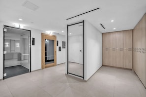 A modern interior with a glass door entrance, a wooden door, and a wall-mounted cabinet. - Brand New Building & Amazing Amenities (Miami)