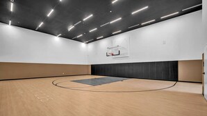 An indoor basketball court with a wooden floor, a basketball hoop, and a wall-mounted rack. - Brand New Building & Amazing Amenities (Miami)