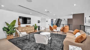 A modern living room with a sofa, chairs, a coffee table, and a TV. - Brand New Building & Amazing Amenities (Miami)