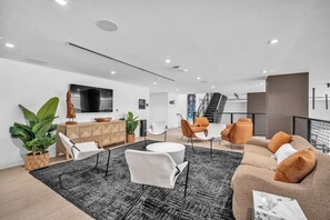 A modern living room with a sofa, chairs, a coffee table, and a TV. - Brand New Building & Amazing Amenities (Miami)
