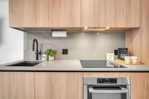 A modern kitchen with a built-in oven, a coffee station, and a sink with a faucet. - Stylish Bay View Studio w/Private Balcony/Downtown (Miami)