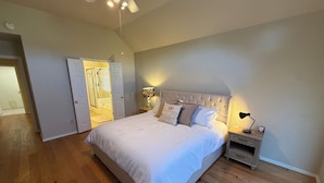 A bedroom with a large bed, a nightstand, a lamp, and a ceiling fan. - Charming 3-bedroom house in peaceful Stillwater with AC (Stillwater)