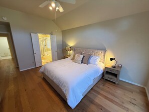A bedroom with a large bed, a nightstand, a lamp, and a ceiling fan. - Charming 3-bedroom house in peaceful Stillwater with AC (Stillwater)