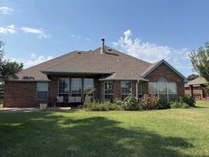A two-story brick house with a covered porch, large windows, and a well-maintained lawn. - Charming 3-bedroom house in peaceful Stillwater, Oklahoma (Stillwater)