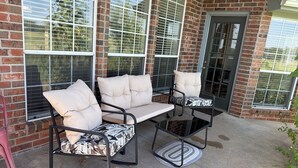 An outdoor patio with a brick wall, large windows, and a metal table and chairs set. - Charming 3-bedroom house in peaceful Stillwater with AC (Stillwater)