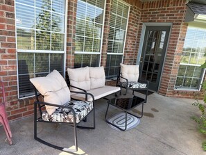 An outdoor patio with a brick wall, large windows, and a metal table and chairs set. - Charming 3-bedroom house in peaceful Stillwater with AC (Stillwater)
