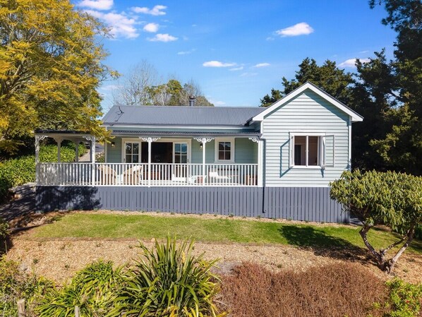 A single-story house with a porch, a fenced yard, and a clear sky.