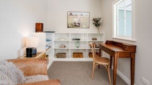 A cozy reading nook with a wooden desk, a comfortable chair, a bookshelf, and a lamp.