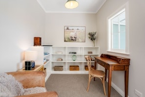 A cozy reading nook with a wooden desk, a comfortable chair, a bookshelf, and a lamp.