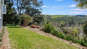 A landscaped garden with a lawn, a variety of shrubs, and trees.